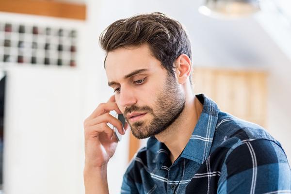 man in a blue checked shirt talking on the phone