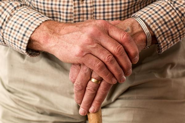 hands of an elderly man balancing on a walking cane