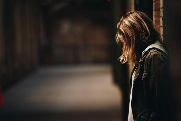 woman standing next to wall against a dark background